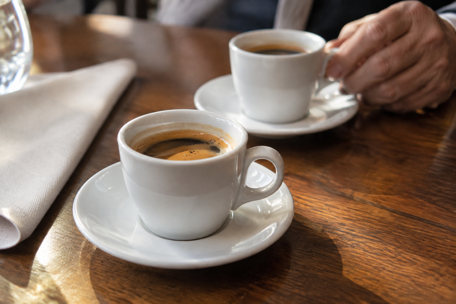 Deux tasses de café sur leurs soucoupes, posées sur une table en bois pour le café de bienvenue.